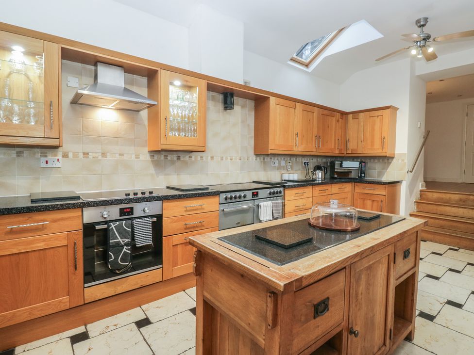 A kitchen with wooden cabinets and appliances at Newlands Fell House in Newlands near Keswick