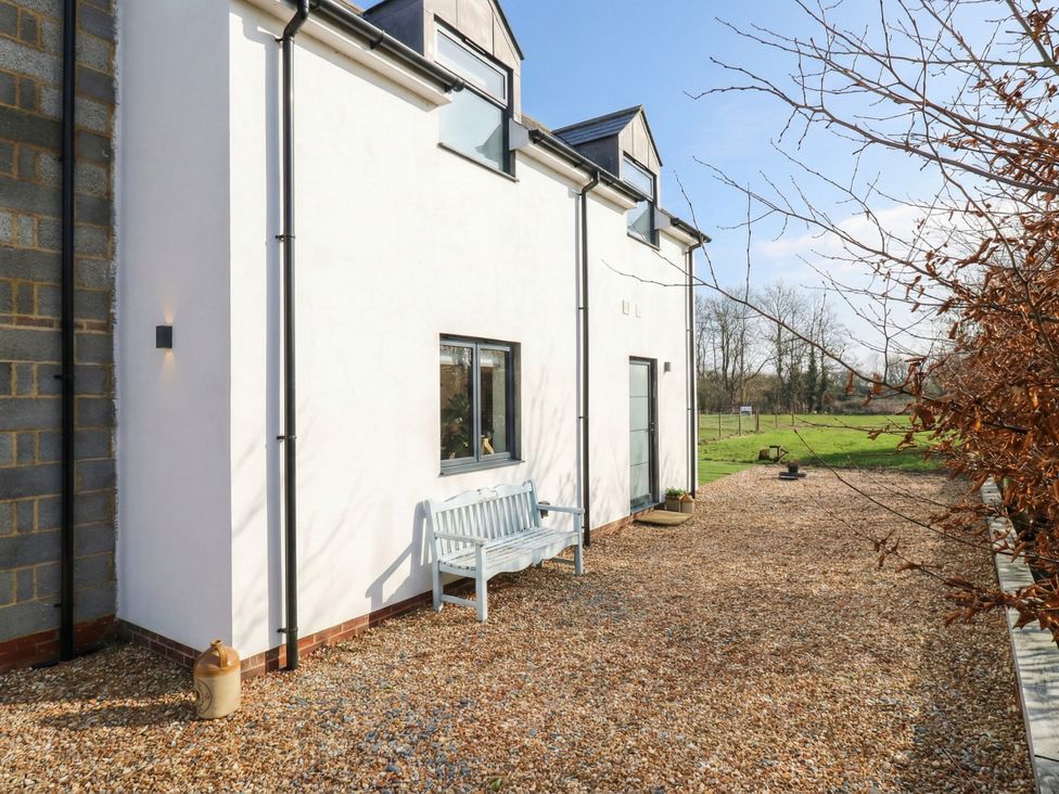 An exterior view of a house with a bench and gravel area at The Kiln in Colmworth