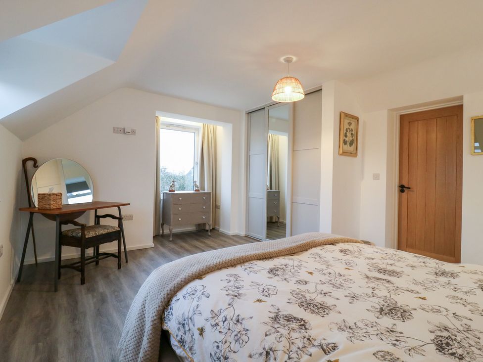 A bedroom with a bed, table, and mirror at The Kiln in Colmworth
