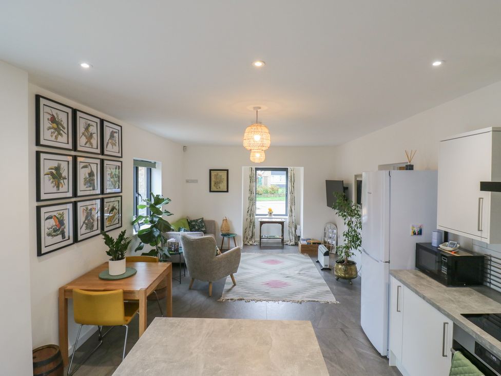A kitchen and living room area with dining table and sofa at The Kiln in Colmworth