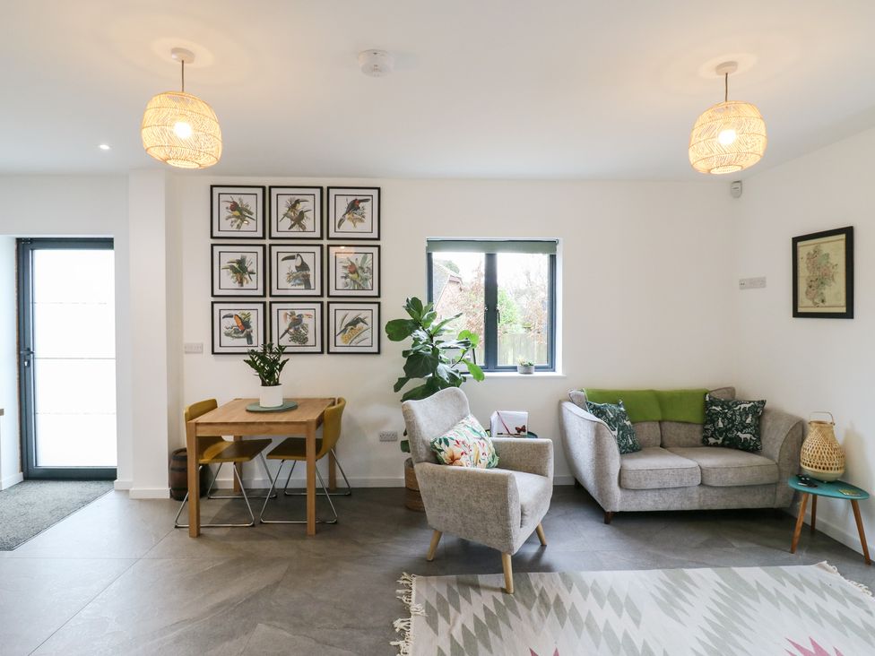 A living room with a sofa a dining table and wall art at The Kiln in Colmworth