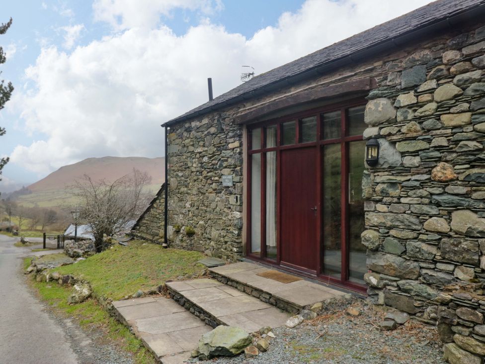 A stone exterior with a wooden door and steps at Newlands Fell Cottage near Keswick