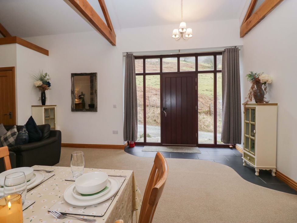 A living room with a dining table and a front door at Newlands Fell Cottage in Newlands near Keswick