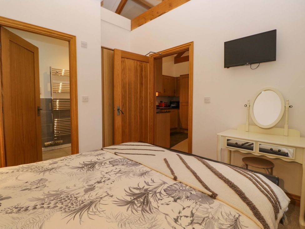 A bedroom with a bed, mirror, and television at Newlands Fell Cottage near Keswick