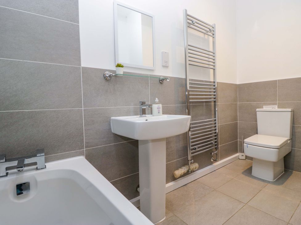 A bathroom with sink, toilet, tub, and towel radiator at Newlands Fell Cottage near Keswick