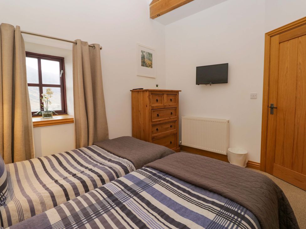 A bedroom with two beds and a television at Newlands Fell Cottage in Newlands near Keswick