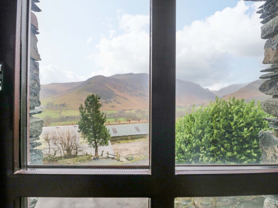 A view of mountains and trees from a window at Newlands Fell Cottage in Newlands near Keswick