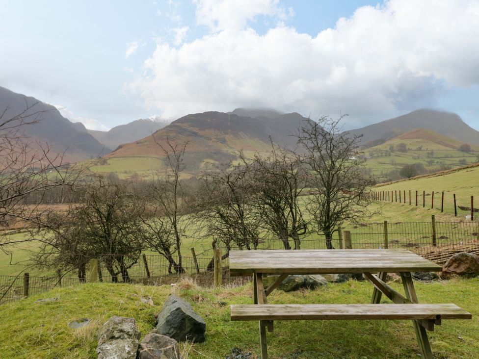 A table near a fence with trees and mountains at Newlands Fell Cottage Newlands near Keswick