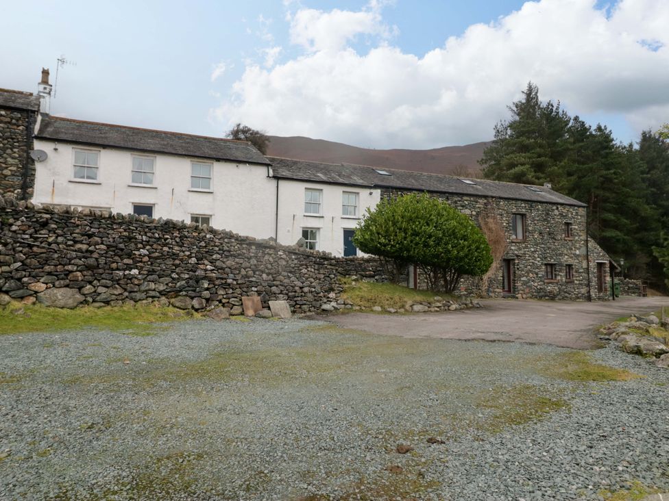 A row of houses with a stone wall and trees at Newlands Fell Cottage in Newlands near Keswick