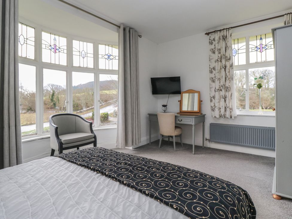 A bedroom with a bed, desk, and windows at Herdwick Croft in Bassenthwaite
