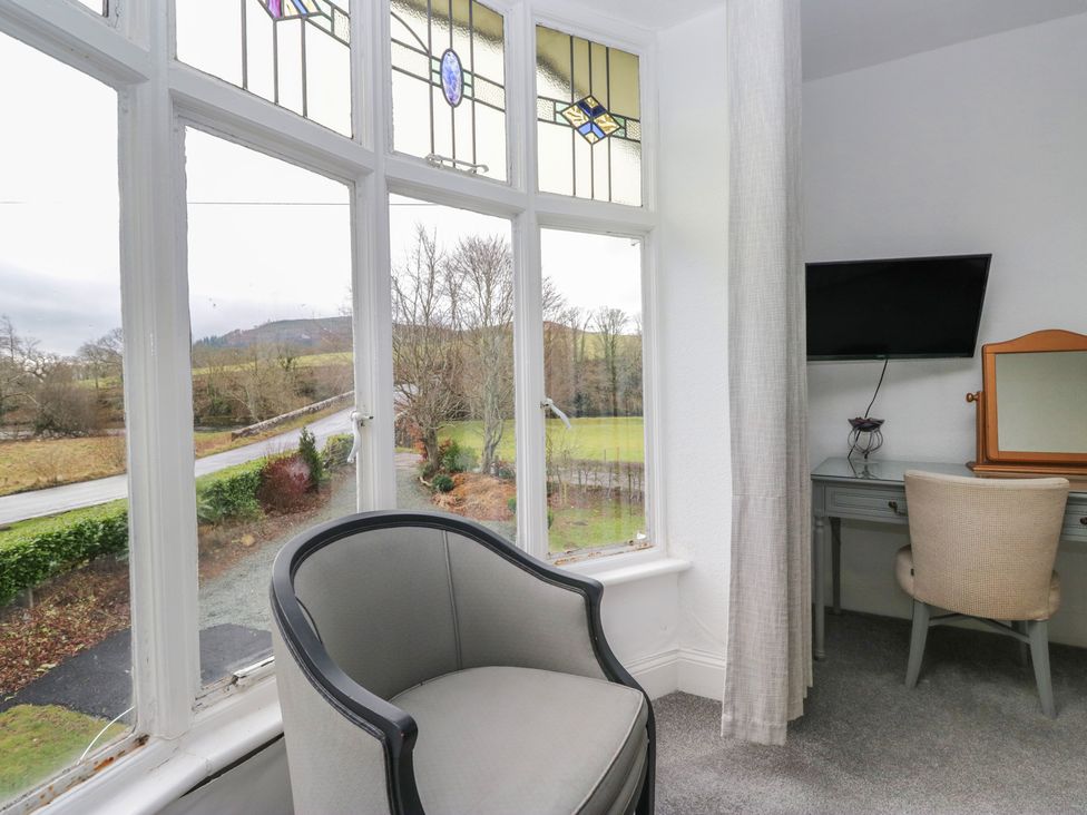 A bedroom with a stained glass window and a wall mounted television at Herdwick Croft in Bassenthwaite