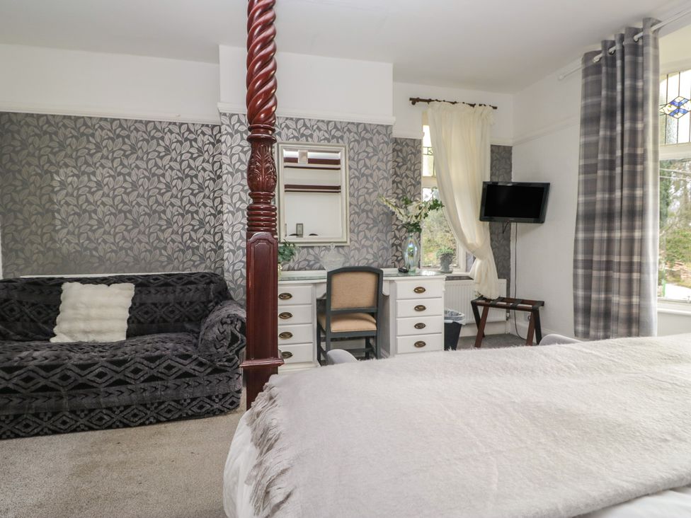 A bedroom with a four-poster bed and a sofa at Herdwick Croft in Bassenthwaite