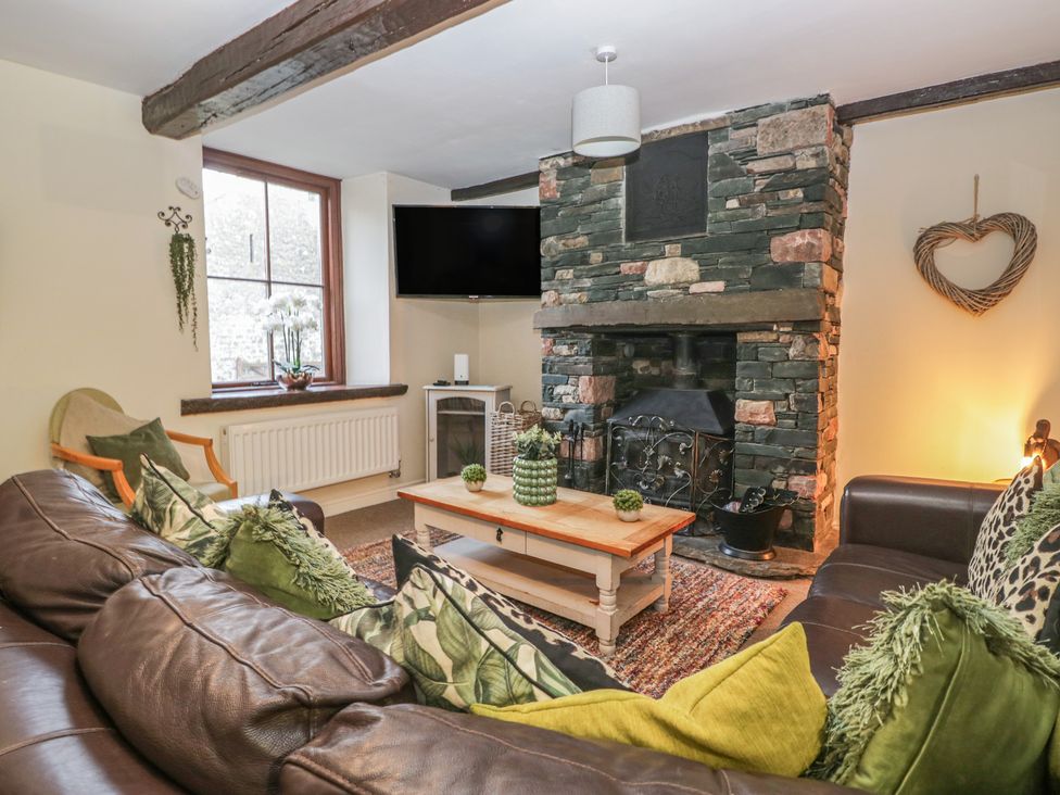 A living room with a stone fireplace and sofa at Birkbank Farm Cockermouth