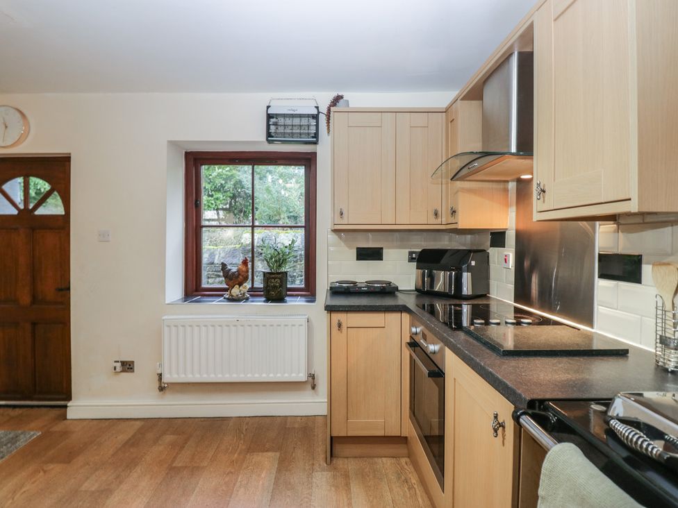 A kitchen with cabinets, countertop, stove, and window at Birkbank Farm in Cockermouth