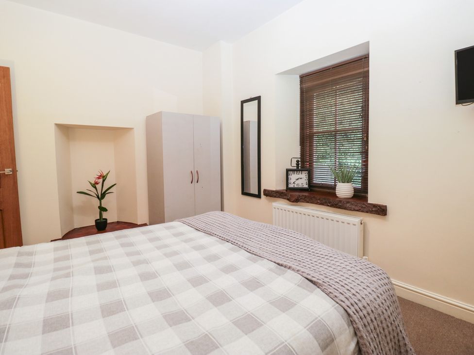 A bedroom featuring a bed, wardrobe, plant, and window at Birkbank Farm in Cockermouth
