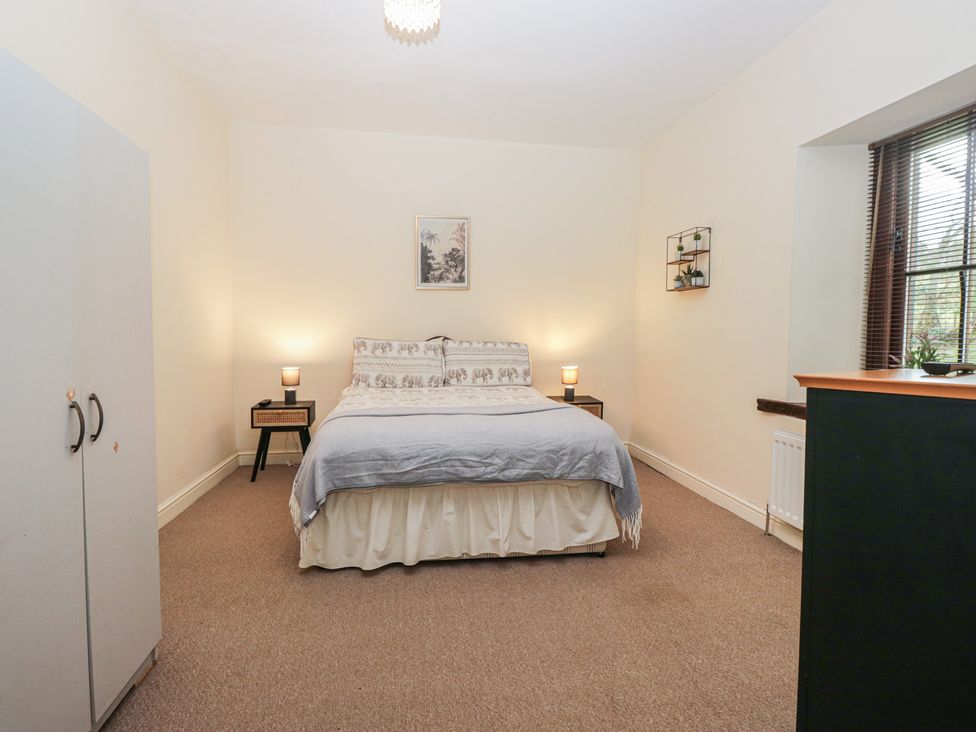 A bedroom with a bed and wardrobe at Birkbank Farm in Cockermouth