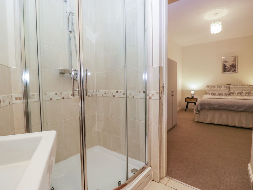 A bathroom with a shower and sink adjoining a bedroom at Birkbank Farm in Cockermouth