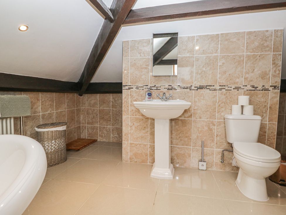 A bathroom with a bathtub, sink, and toilet at Birkbank Farm in Cockermouth