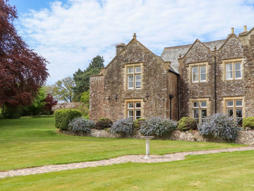 An outdoor view of a stone building with garden at Dowrich West Wing Apartment in Crediton