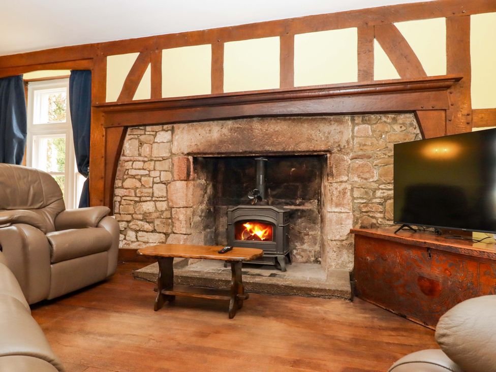 A living room with a fireplace and a television at Dowrich West Wing Apartment in Crediton