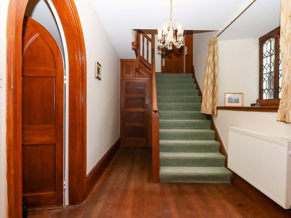 A hallway with a staircase and wooden doors at Dowrich West Wing Apartment in Crediton