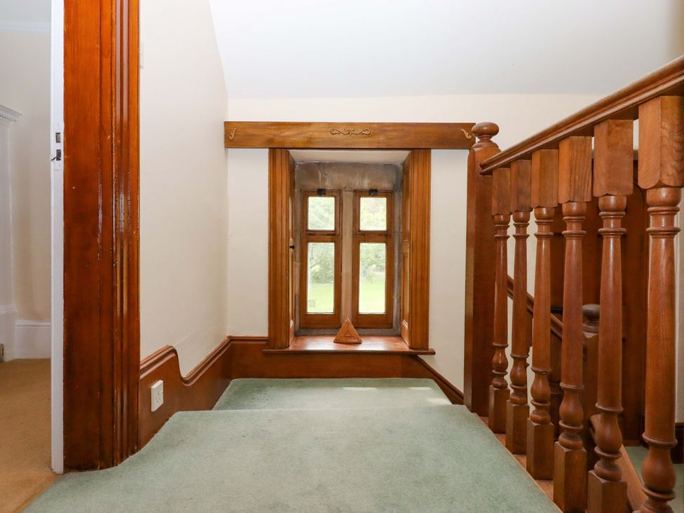 A hallway with a wooden railing and window at Dowrich West Wing Apartment Crediton