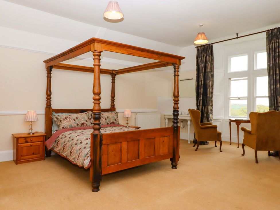 A bedroom with a four-poster bed and chairs at Dowrich West Wing Apartment in Crediton