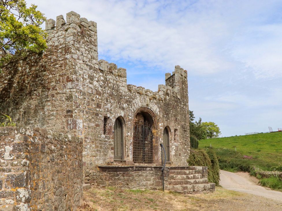 A castle structure with a gate and stairs near a road at Dowrich West Wing Apartment in Crediton