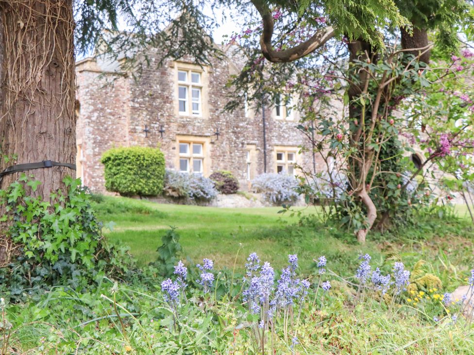 An outdoor area with flowers and a building in the background at Dowrich West Wing Apartment in Crediton