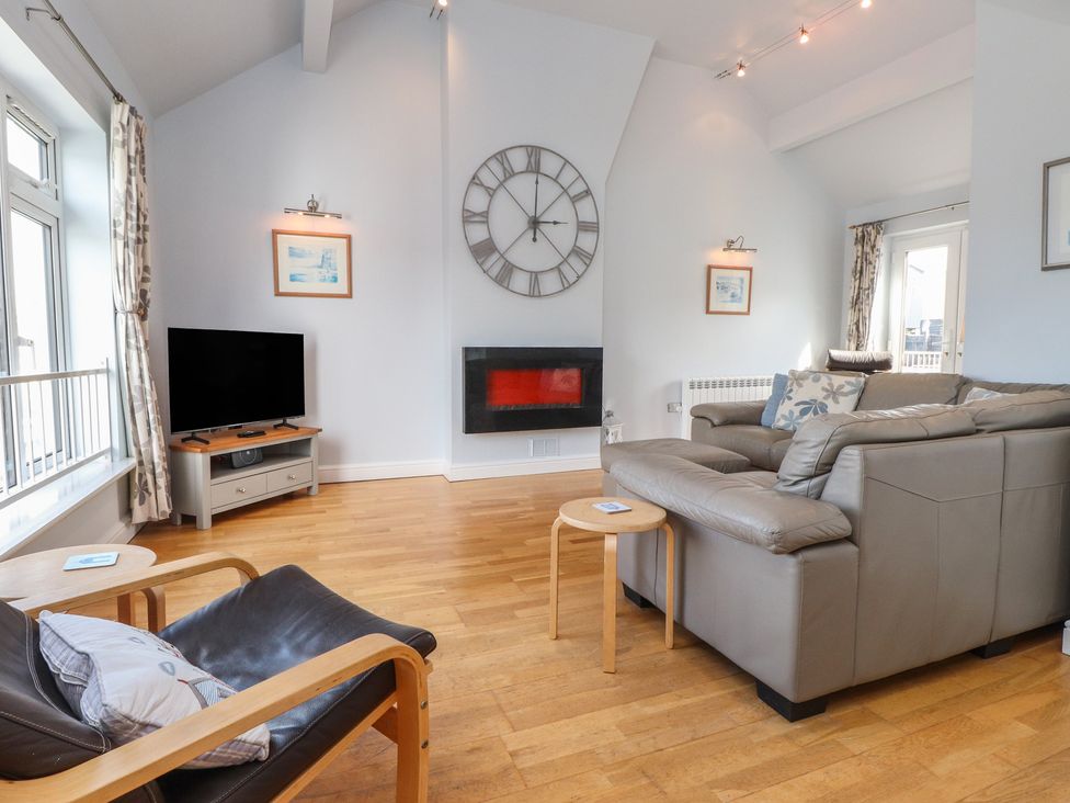 A living room with a sofa, TV, and fireplace at Flat 1