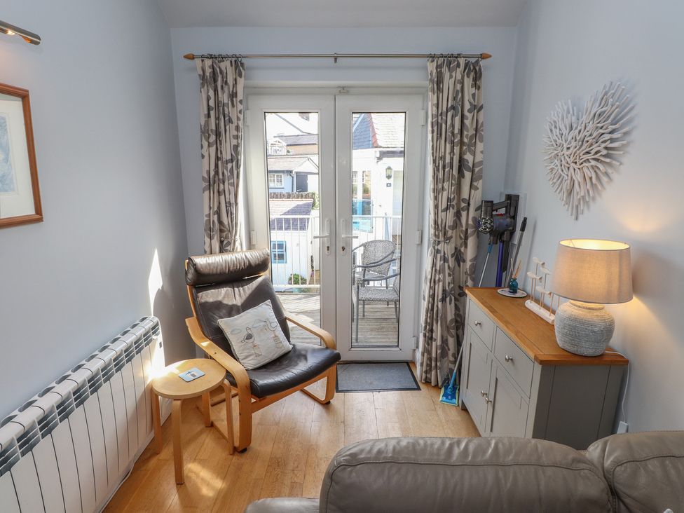 A living room with an armchair and door leading to the outside at Flat 1