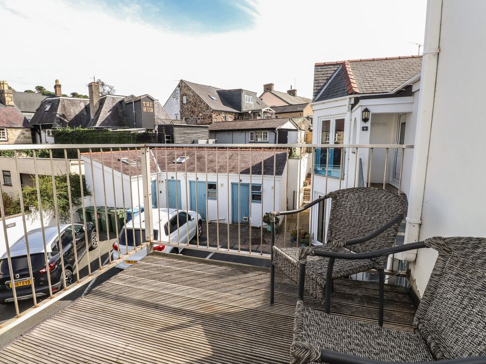 A balcony with chairs overlooking buildings and parked cars at Flat 1