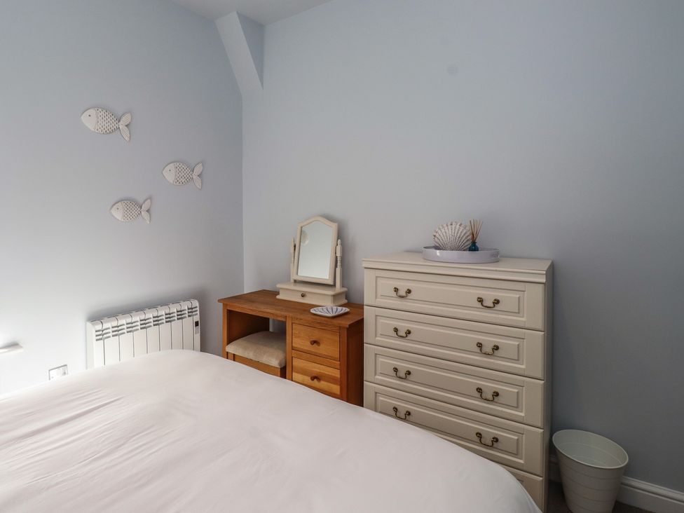 A bedroom with a bed, dresser, and mirror at Flat 1