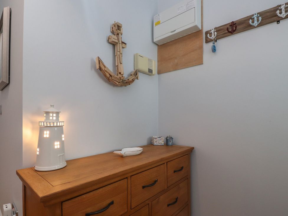 A hallway with a lighthouse lamp and wooden anchor at Flat 1