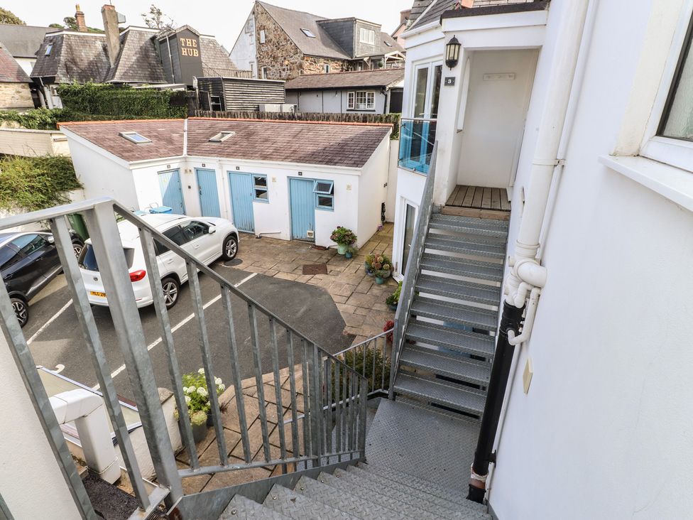 A staircase overlooking an outdoor area with garages and parked cars at Flat 1