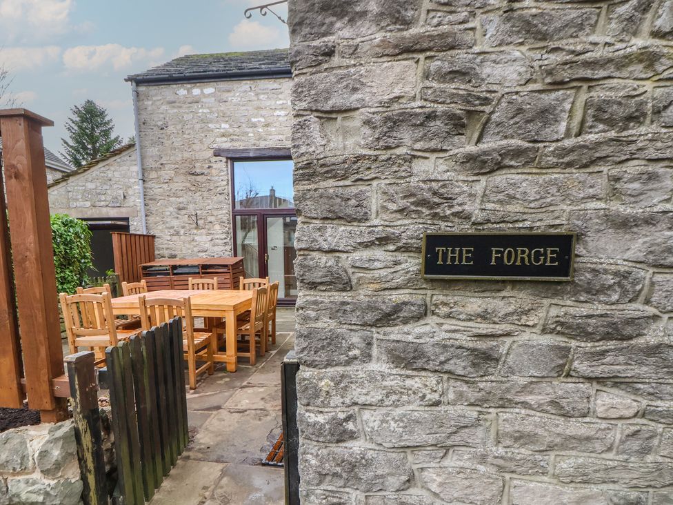 An outdoor area with a stone wall and furniture at The Forge in Castleton, Peak District