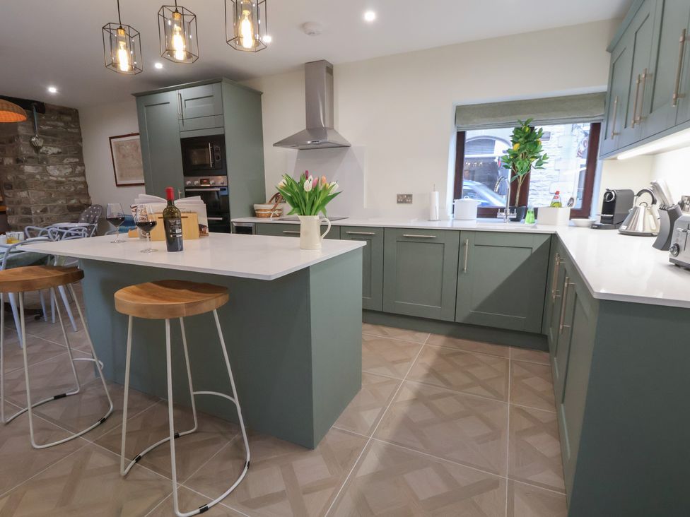 A kitchen with a center island and bar stools at The Forge in Castleton, Peak District