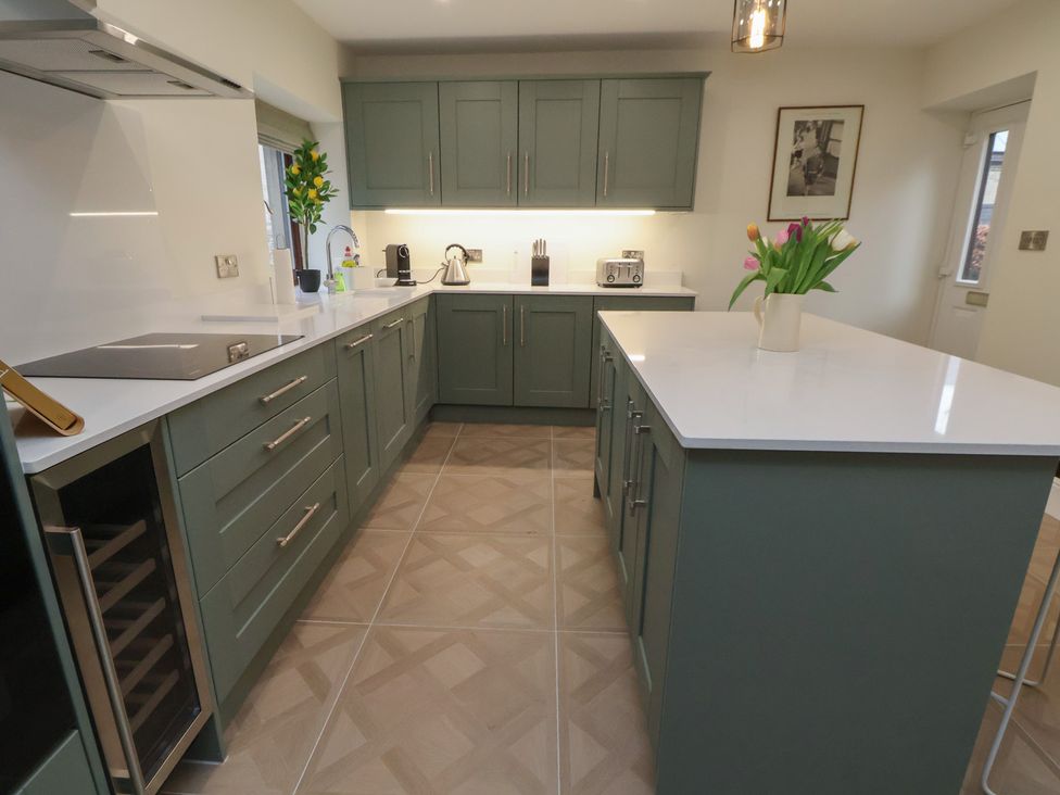 A kitchen with cabinets, appliances and a vase of tulips at The Forge in Castleton, Peak District
