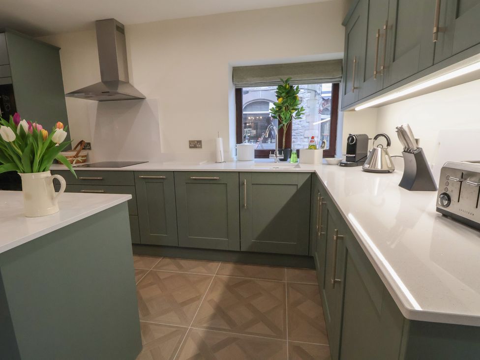 A kitchen with green cabinets and a window at The Forge in Castleton, Peak District