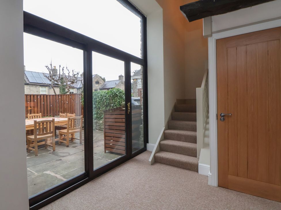 A hallway with a staircase and a glass door leading outside at The Forge in Castleton, Peak District