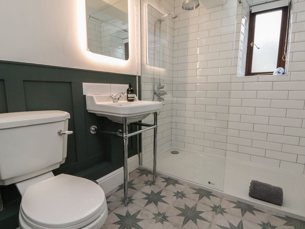 A bathroom with a toilet, sink, shower, and window at The Forge in Castleton, Peak District