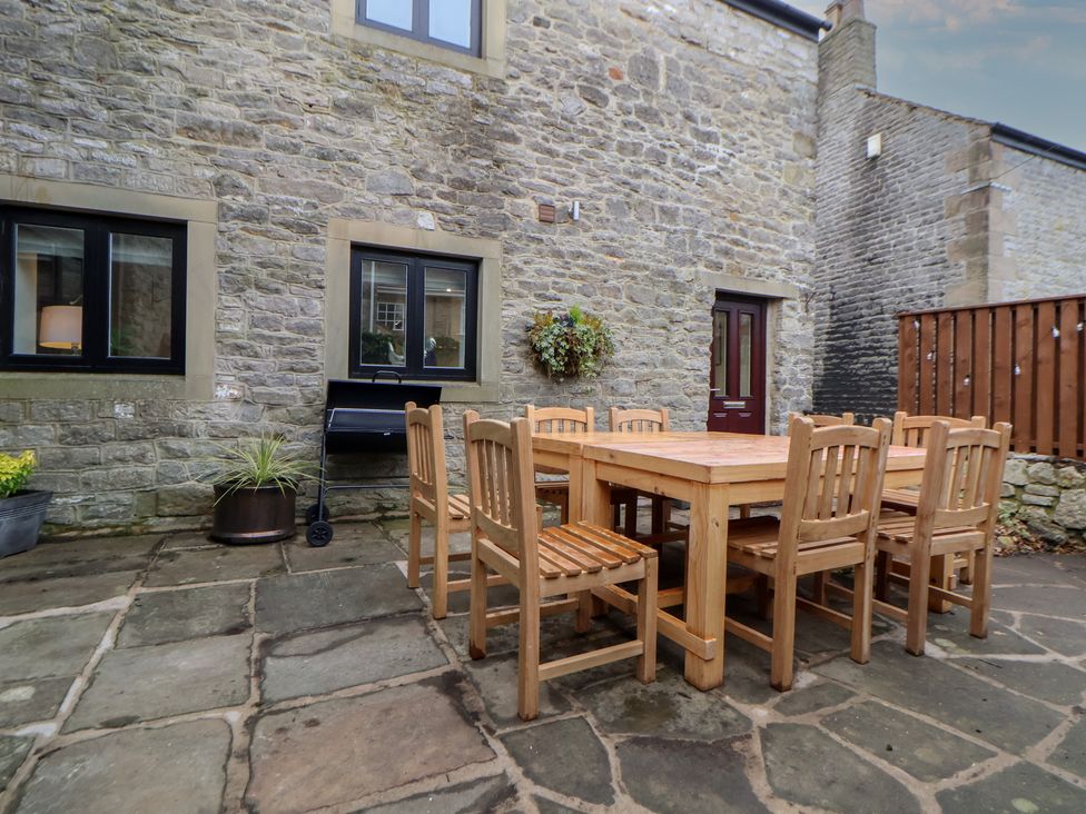 An outdoor dining area with a wooden table and chairs at The Forge in Castleton, Peak District