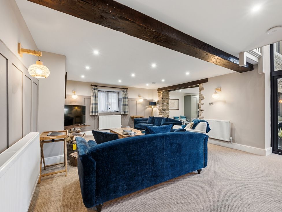 A living room with a sofa, armchair, and television at The Forge in Castleton, Peak District