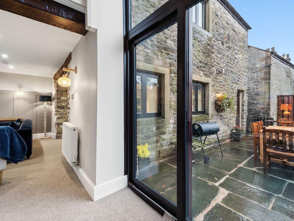 A living room with a sofa and a view of a patio at The Forge in Castleton, Peak District