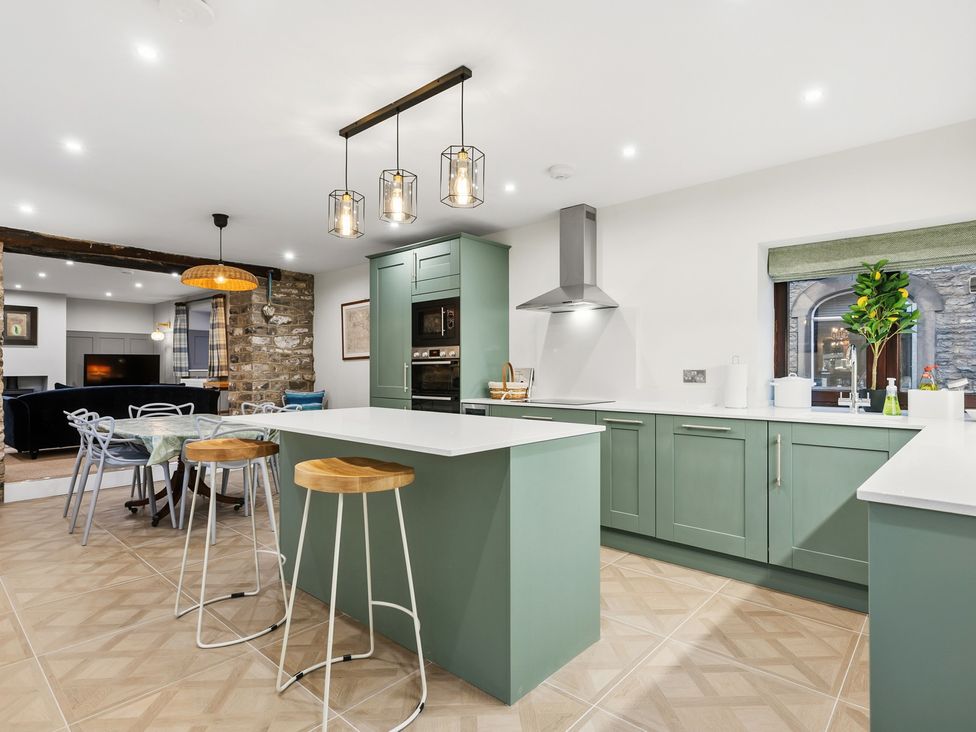 A kitchen with a green island and stools at The Forge in Castleton, Peak District