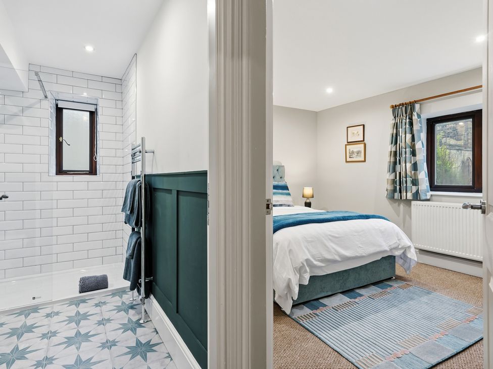 A bathroom with a shower and a bedroom with a bed at The Forge in Castleton, Peak District