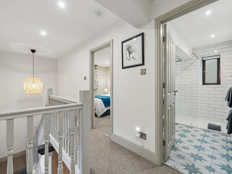 A hallway with a staircase and a bathroom door at The Forge in Castleton, Peak District