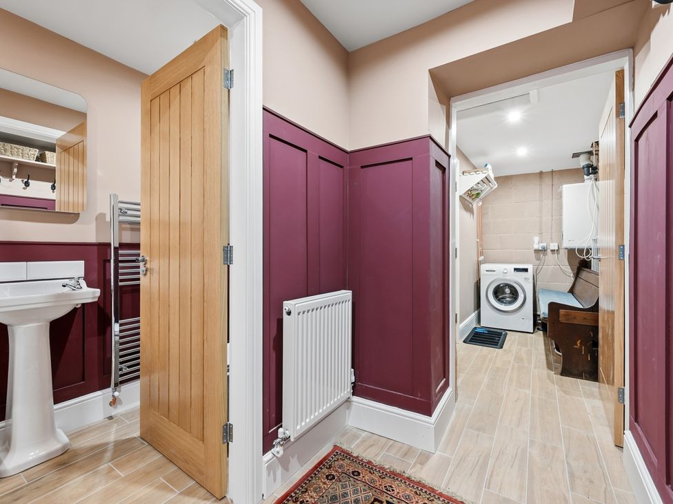 A bathroom with a sink, mirror, and washing machine at The Forge in Castleton, Peak District