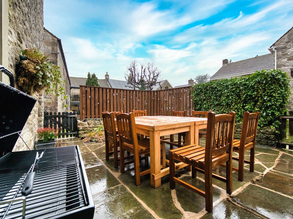 A patio area with a wooden table and chairs at The Forge Castleton, Peak District