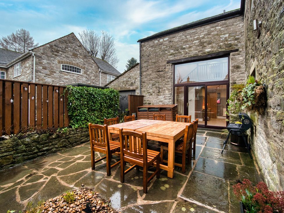 A garden with a wooden table and chairs at The Forge in Castleton, Peak District
